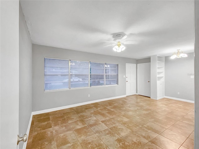 tiled empty room featuring ceiling fan with notable chandelier