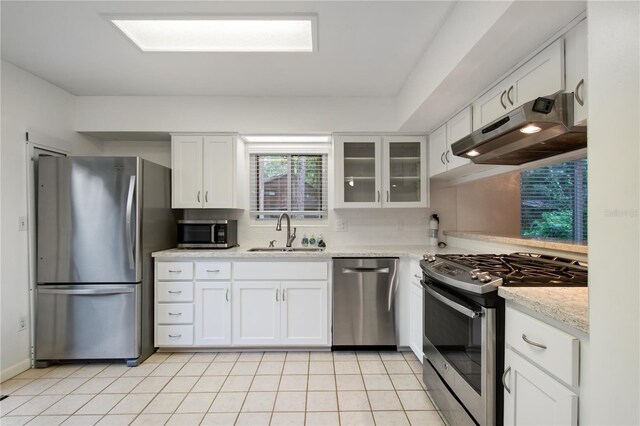 kitchen featuring white cabinets, sink, appliances with stainless steel finishes, light tile patterned floors, and backsplash