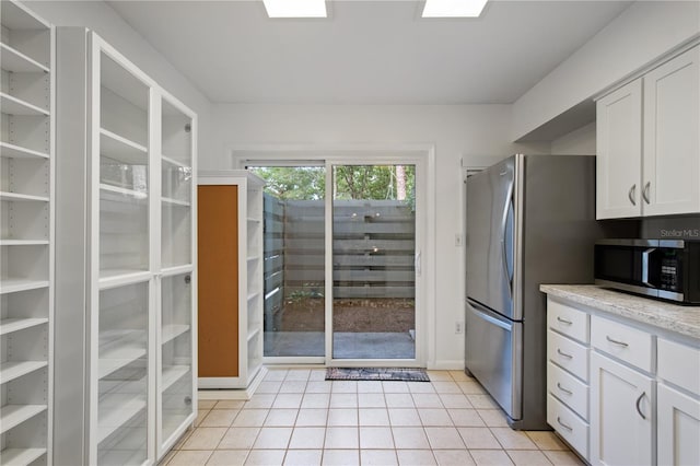 kitchen with appliances with stainless steel finishes, light tile patterned floors, and white cabinets