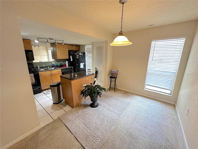 kitchen with decorative light fixtures, black appliances, light carpet, a textured ceiling, and track lighting