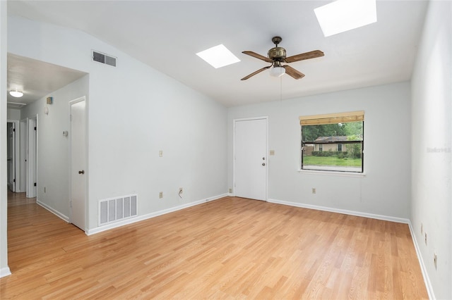 empty room featuring vaulted ceiling with skylight, visible vents, and light wood-style floors