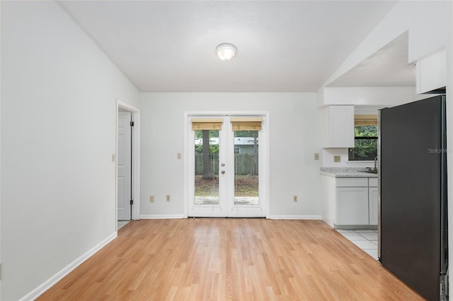 interior space featuring white cabinets, light wood finished floors, light countertops, and freestanding refrigerator