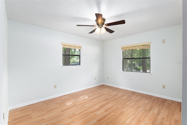 empty room with baseboards, light wood-type flooring, and a healthy amount of sunlight