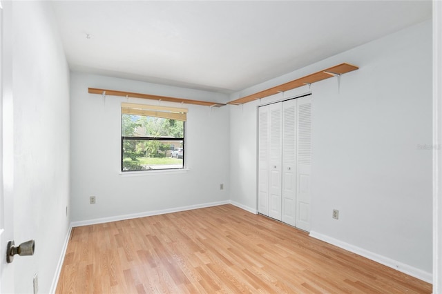 unfurnished bedroom with light wood-style floors, a closet, and baseboards