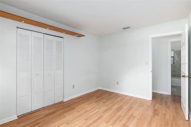 unfurnished bedroom with a closet, baseboards, visible vents, and light wood finished floors