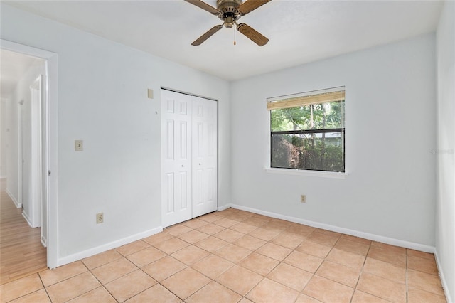 unfurnished bedroom featuring ceiling fan, a closet, light tile patterned flooring, and baseboards