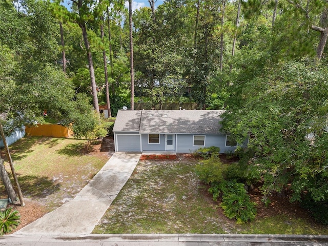 ranch-style house with driveway, fence, and a front lawn