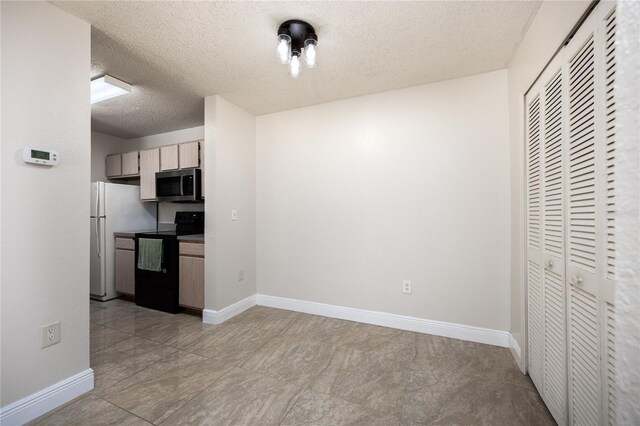 kitchen featuring black range with electric stovetop, a textured ceiling, and white fridge