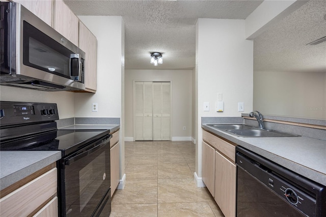 kitchen with sink, light tile patterned floors, black appliances, light brown cabinets, and a textured ceiling