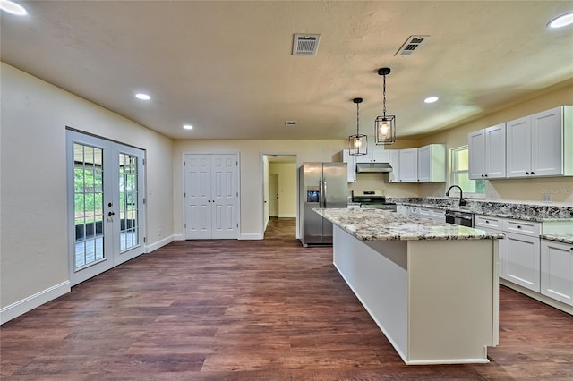 kitchen featuring pendant lighting, appliances with stainless steel finishes, light stone countertops, white cabinets, and a kitchen island