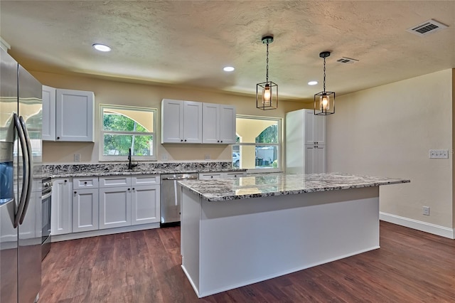 kitchen featuring white cabinetry, stainless steel appliances, a center island, and dark wood-type flooring