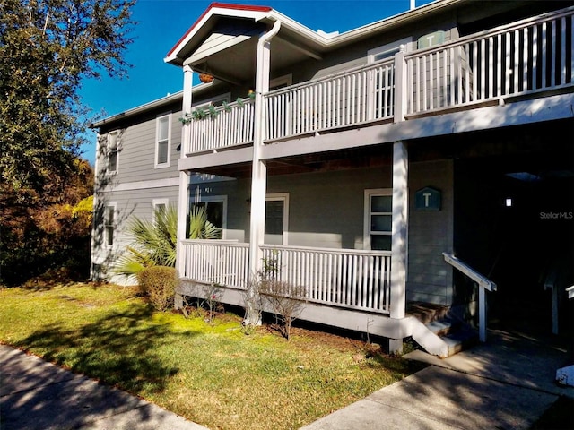 back of house featuring a balcony and a lawn