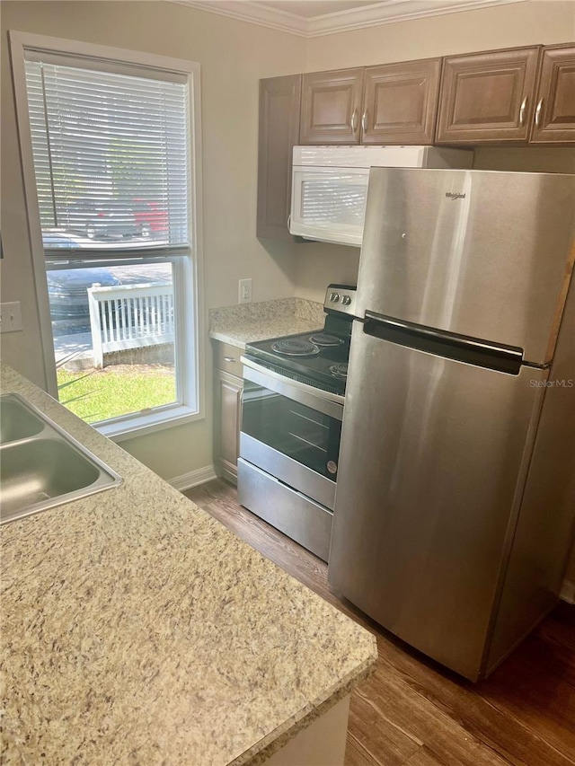 kitchen with stainless steel appliances, ornamental molding, sink, and hardwood / wood-style flooring