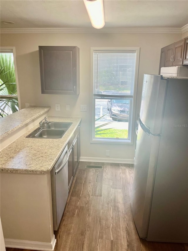 kitchen featuring crown molding, hardwood / wood-style flooring, stainless steel appliances, and sink