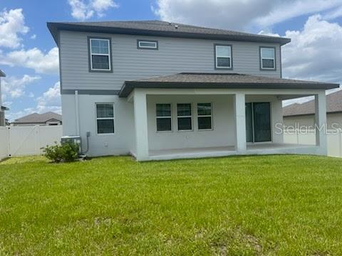 rear view of house featuring cooling unit, a lawn, and a patio area