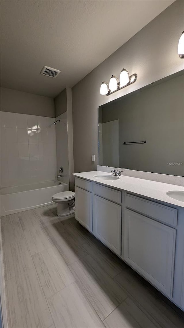 full bathroom featuring vanity, tiled shower / bath combo, a textured ceiling, and toilet