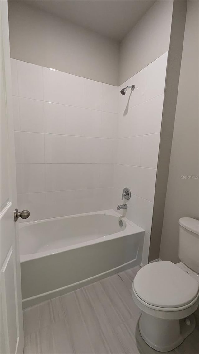 bathroom featuring tiled shower / bath combo and toilet