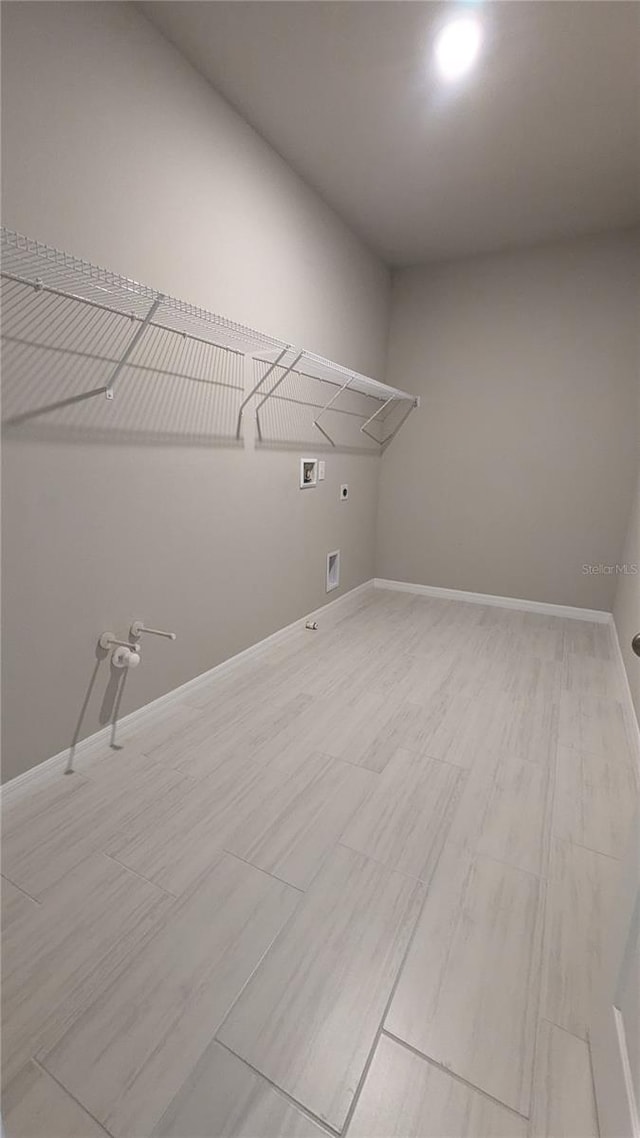 clothes washing area featuring electric dryer hookup, hookup for a washing machine, light hardwood / wood-style flooring, and gas dryer hookup