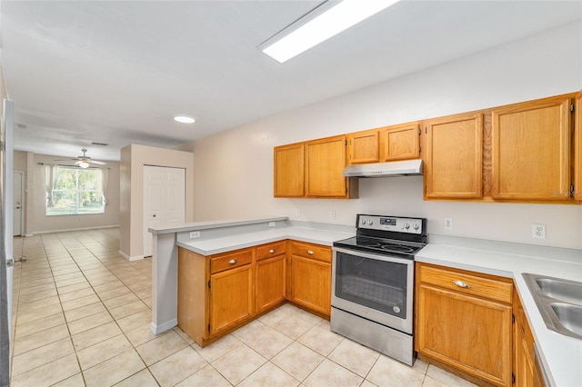 kitchen featuring light tile patterned floors, a peninsula, light countertops, stainless steel range with electric cooktop, and under cabinet range hood