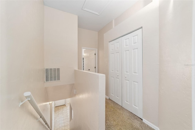 corridor with baseboards, visible vents, and an upstairs landing