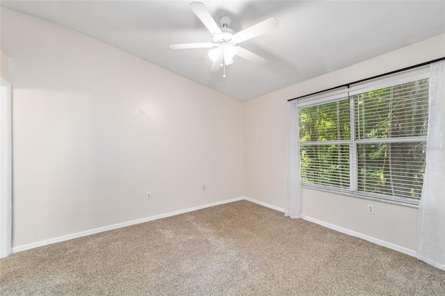 carpeted spare room with ceiling fan and baseboards