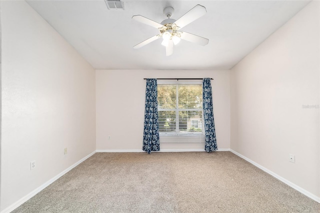 carpeted spare room featuring a ceiling fan, visible vents, and baseboards