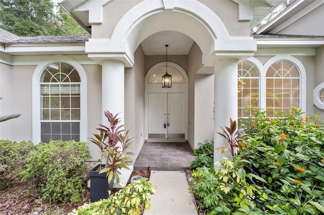 property entrance featuring roof with shingles and stucco siding