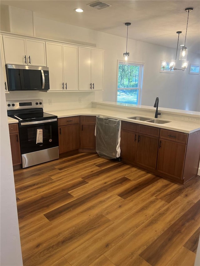 kitchen featuring white cabinetry, sink, stainless steel appliances, and decorative light fixtures