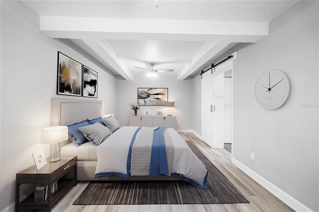 bedroom featuring light hardwood / wood-style flooring, a barn door, and ceiling fan