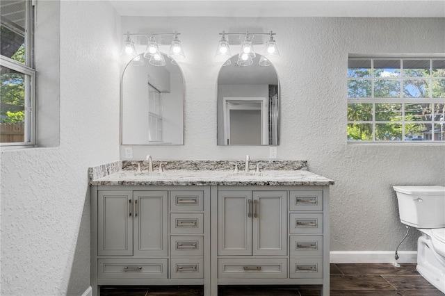 bathroom featuring dual vanity, toilet, and hardwood / wood-style floors