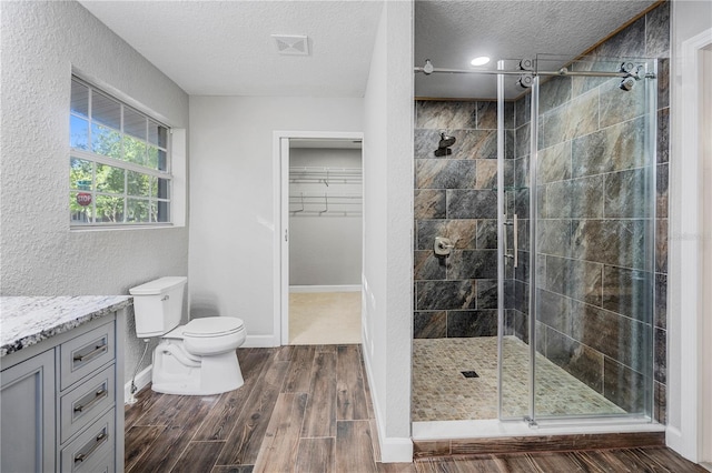 1022 NE 8th Ave, Gainesville, FL 32601 - bathroom featuring a textured ceiling, toilet, a shower stall, vanity, and a walk in closet