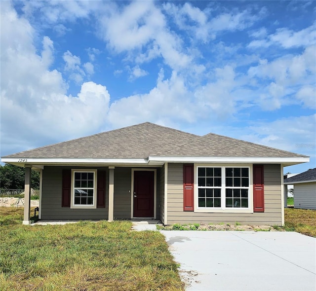 view of front of property with roof with shingles and a front lawn