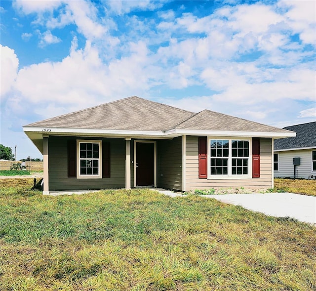 view of front of house with a front lawn and a shingled roof