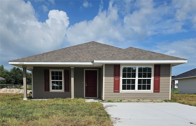 bungalow-style house with a porch, roof with shingles, and a front lawn