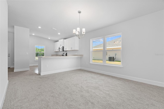 kitchen featuring stainless steel microwave, light colored carpet, vaulted ceiling, recessed lighting, and white cabinetry