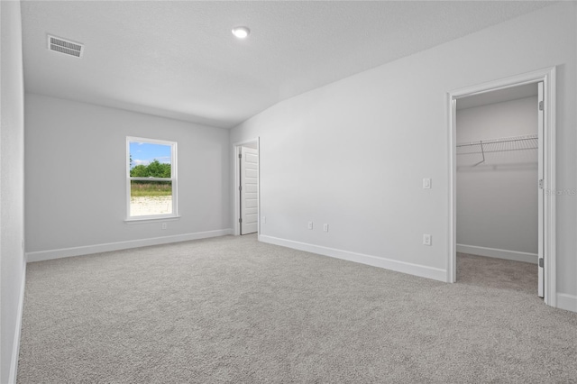 unfurnished bedroom featuring visible vents, a walk in closet, baseboards, and carpet floors