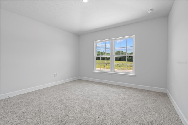 carpeted spare room featuring baseboards