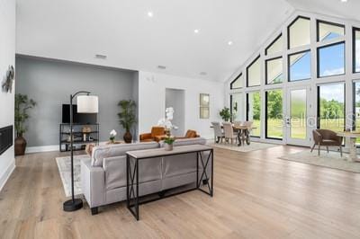 living room with high vaulted ceiling and light hardwood / wood-style floors