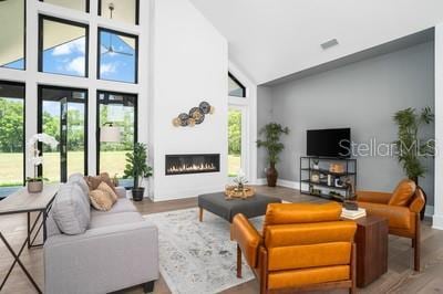 living room with hardwood / wood-style flooring, plenty of natural light, and high vaulted ceiling