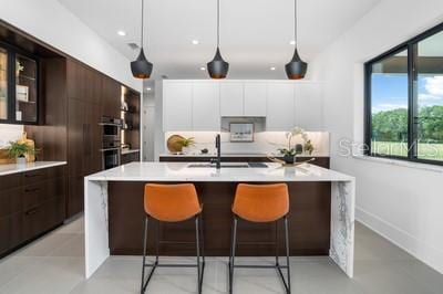 kitchen with hanging light fixtures, stainless steel double oven, white cabinets, and dark brown cabinetry