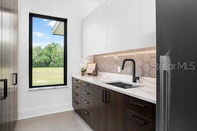 kitchen featuring stainless steel refrigerator, sink, white cabinets, decorative backsplash, and dark brown cabinets