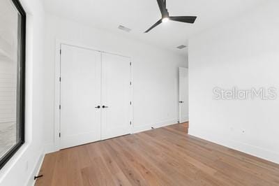 unfurnished bedroom featuring ceiling fan, light hardwood / wood-style floors, and a closet