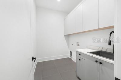 laundry room featuring sink, cabinets, dark tile patterned floors, washer hookup, and hookup for an electric dryer