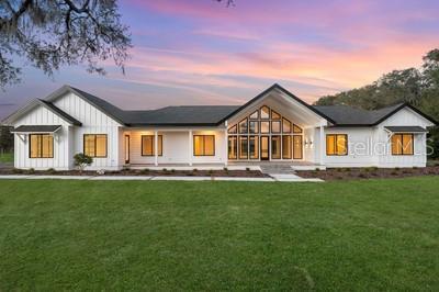 back house at dusk featuring a lawn