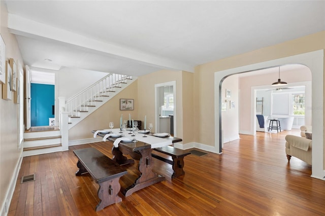 dining space with beam ceiling, a healthy amount of sunlight, and hardwood / wood-style flooring