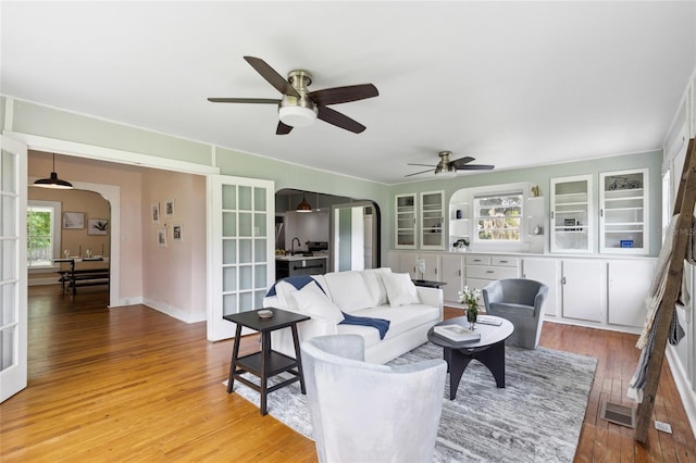 living room featuring french doors, light hardwood / wood-style flooring, ceiling fan, and sink