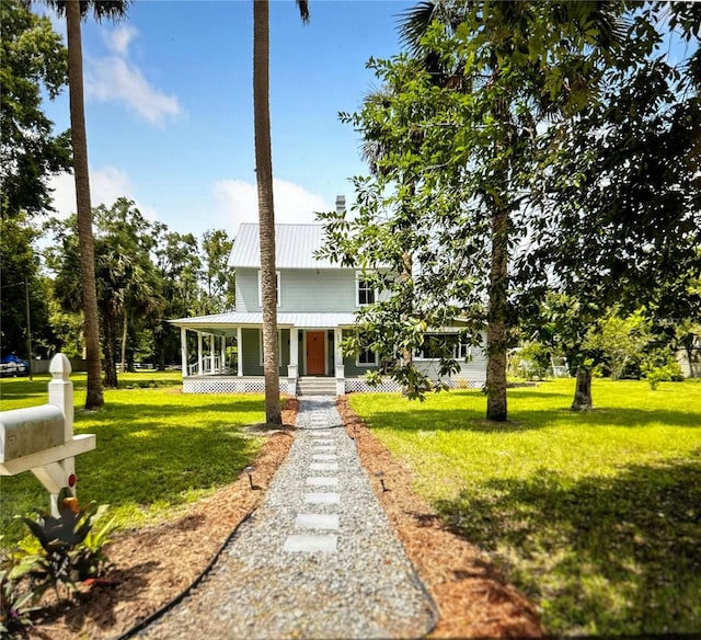 country-style home featuring metal roof, a porch, and a front yard