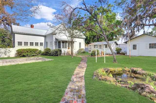 view of front of house featuring an outbuilding, a patio, and a front yard