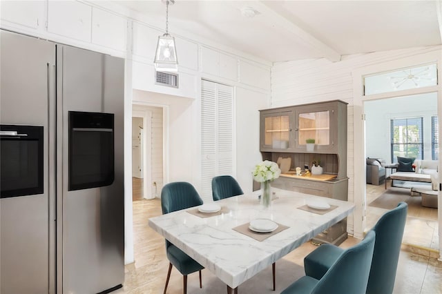 dining space featuring beamed ceiling