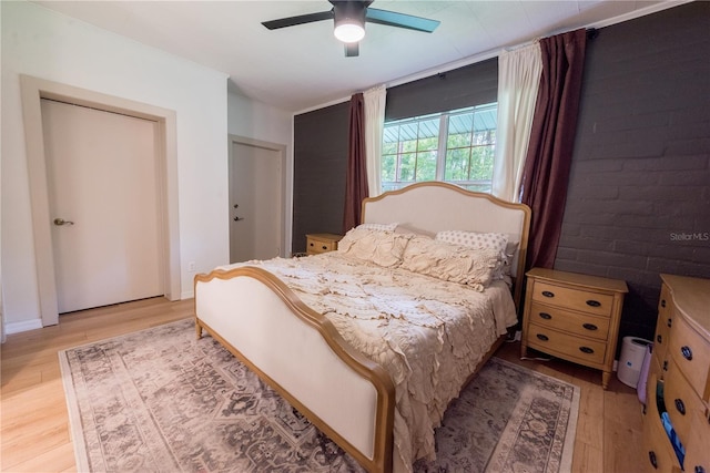 bedroom featuring brick wall, ceiling fan, and light hardwood / wood-style flooring